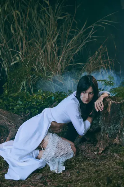 Una donna in abito bianco posa in una foresta. — Foto stock