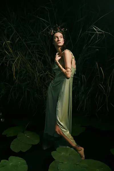A woman wearing a green dress poses near a swamp at dusk. — Stock Photo