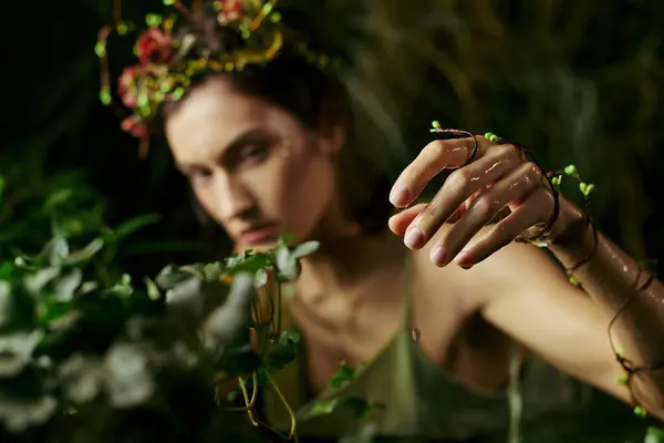 Une femme en tenue fluide pose près d'un marais, la main tendue pour toucher une vigne délicate. — Photo de stock