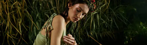 A woman in a flowing green dress poses in a swamp setting. — Stock Photo