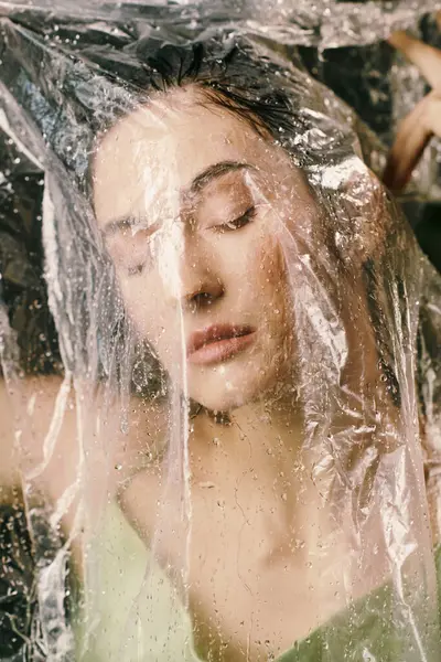A womans face partly hidden, evoking a dreamy feel, with plastic draped over her. — Stock Photo