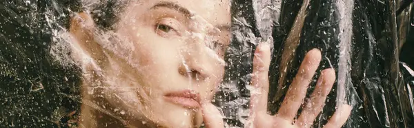 A woman poses near a swamp, water droplets, with plastic draped over her. — Stock Photo
