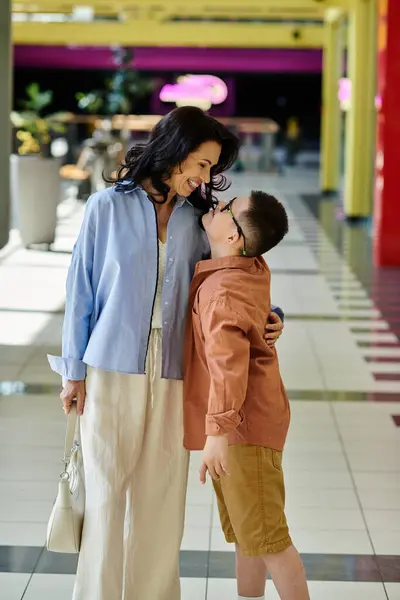 Una madre y su hijo con síndrome de Down comparten un momento tierno durante una excursión al centro comercial. - foto de stock