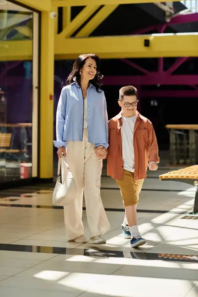 A mother and her son with Down syndrome walk hand-in-hand through a shopping mall, enjoying their time together. — Stock Photo