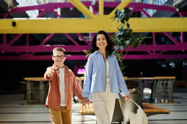A mother and her son with Down syndrome walk hand-in-hand through a shopping mall, enjoying a day out together. — Stock Photo
