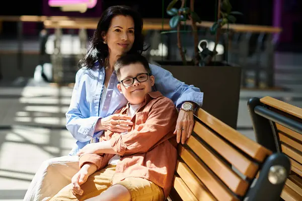 Una madre y su hijo con síndrome de Down comparten un momento reconfortante en un centro comercial. - foto de stock