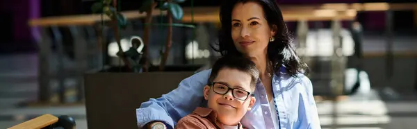 A mother and her son with Down syndrome are seen walking together in a shopping mall, enjoying each others company. — Stock Photo