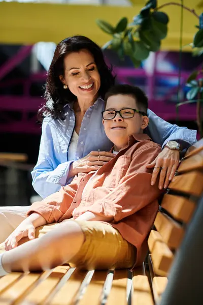 A mother and her son with Down syndrome share a heartwarming moment on a bench in a shopping mall. — Stock Photo