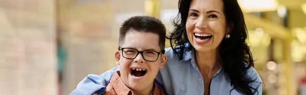 A mother and her son with Down syndrome are walking through a shopping mall, smiling and laughing together. — Stock Photo