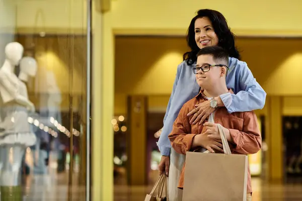 A mother lovingly embraces her son with Down syndrome as they walk through a shopping mall, enjoying a day out together. — Stock Photo