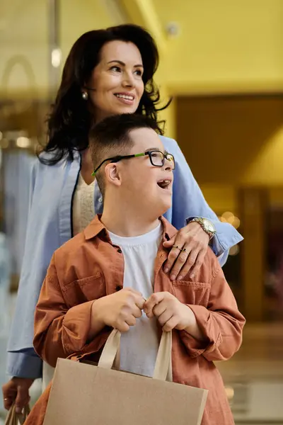 A mother and her son with Down syndrome share a happy moment while shopping in a mall. — Stock Photo