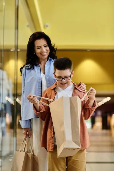 A mother and her son with Down syndrome are walking through a shopping mall, enjoying a day of shopping and bonding. — Stock Photo