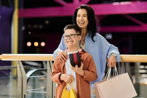 Мать и ее сын с синдромом Дауна вместе ходят по магазинам в торговом центре, оба носят сумки и выглядят счастливыми.. — стоковое фото