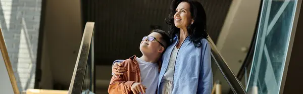 A mother and her son with Down syndrome share a warm embrace while walking through a shopping mall. — Stock Photo