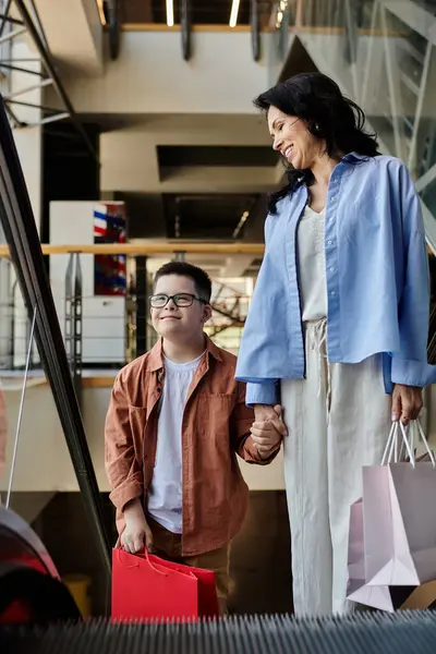 A mother and her son with Down syndrome walk hand-in-hand through a shopping mall, enjoying their time together. — Stock Photo