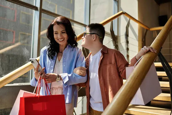 Una madre y su hijo con síndrome de Down están de compras juntos en un centro comercial, llevando bolsas de la compra. — Stock Photo