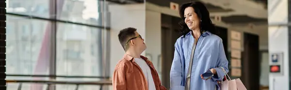 Мать и ее сын с синдромом Дауна наслаждаются вместе походами по магазинам, разделяя счастливый момент в торговом центре. — стоковое фото