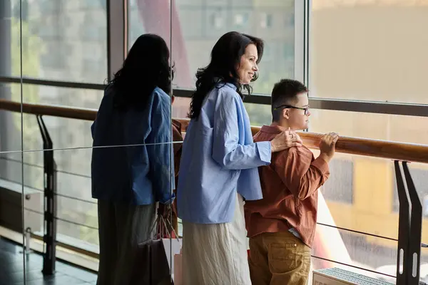 A mother and her son with Down syndrome are enjoying a walk through the shopping mall. — Stock Photo