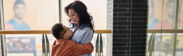 A mother lovingly embraces her son, who has Down syndrome in a shopping mall. — Stock Photo