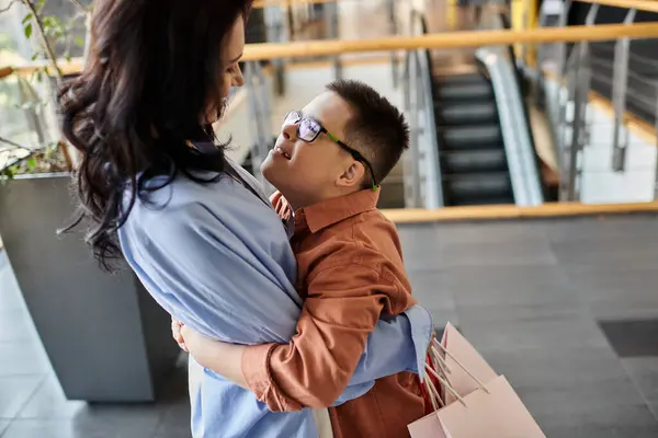 A mother and her son with Down syndrome share a heartwarming embrace in a shopping mall. — Stock Photo