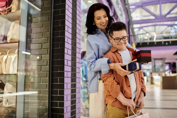 A mother and son with Down syndrome spend quality time together, smiling as they exchange a gift at a shopping mall. — Stock Photo