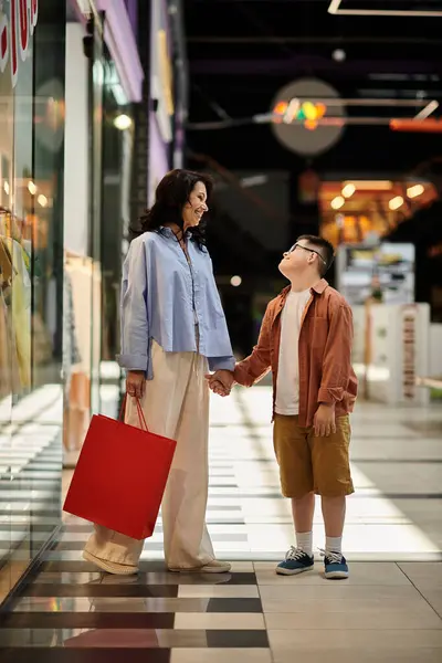 A mother and her son with Down syndrome enjoy a shopping trip together in a mall. — Stock Photo