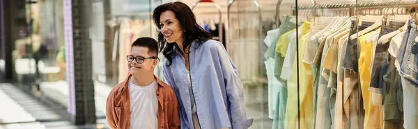 A mother and her son with Down syndrome walk together in a shopping mall, enjoying a day out. — Stock Photo