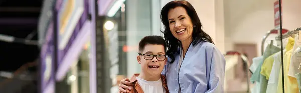 Una madre e suo figlio con la sindrome di Down stanno camminando in un centro commerciale, godendo la loro giornata insieme. — Foto stock
