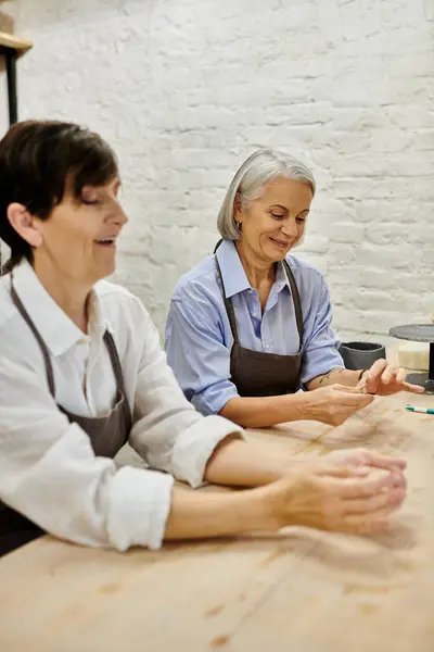 Two mature lesbians working on pottery in a studio. — Stock Photo