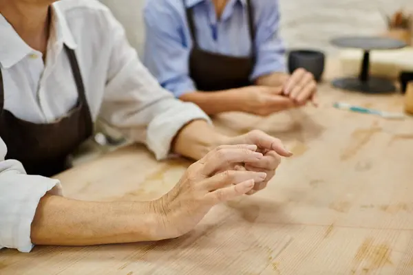 Un gros plan d'une lesbienne couple les mains tout en fabriquant dans un studio de poterie confortable. — Photo de stock
