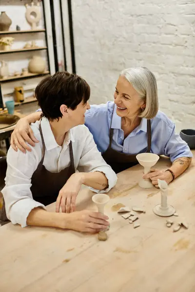 Two women, a mature lesbian couple, happily create pottery together in a cozy art studio. — Stock Photo