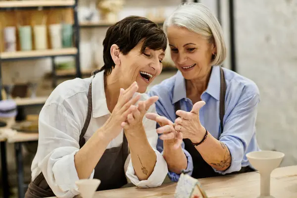 Two women are laughing together while crafting at a pottery studio. — Stock Photo