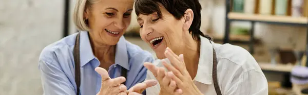 Two mature women, a lesbian couple, work together on a pottery project in a cozy art studio. — Stock Photo