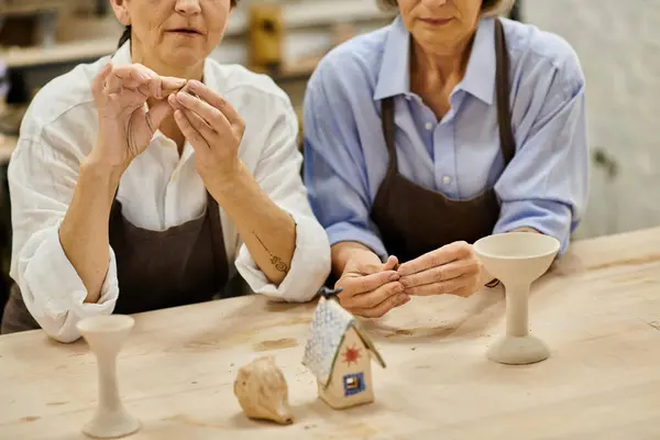 Duas mulheres maduras trabalham em projetos de cerâmica em um estúdio de arte acolhedor. — Fotografia de Stock