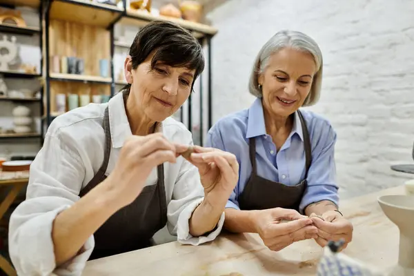 Two women work on pottery in a studio, focused on their craft. — Stock Photo