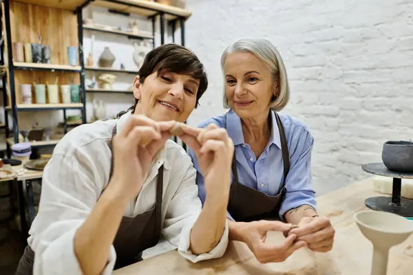 Two mature women, a lesbian couple, work on pottery in a cozy studio setting. — Stock Photo