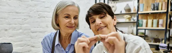 Two women, a mature lesbian couple, work on pottery projects in a cozy studio. — Stock Photo