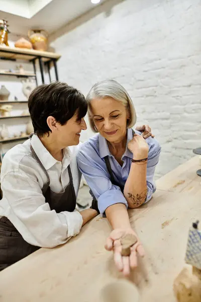 Two women in cozy attire craft pottery together in an art studio. — Stock Photo