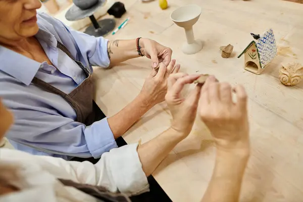 A mature lesbian couple works on pottery in a cozy art studio. — Stock Photo