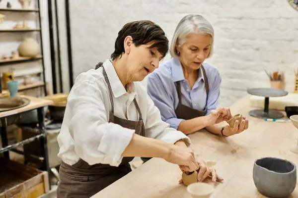 Two mature women are working with clay in an art studio. — Stock Photo