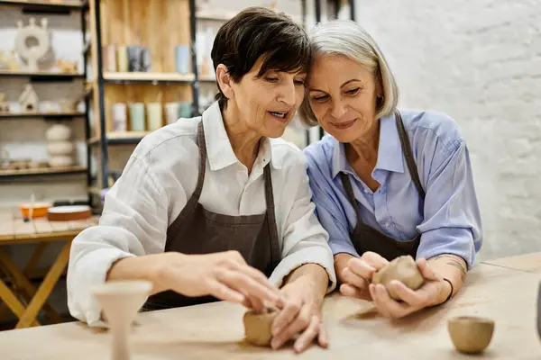 Two mature women in a pottery studio, working with clay, a loving and cozy scene. — Stock Photo
