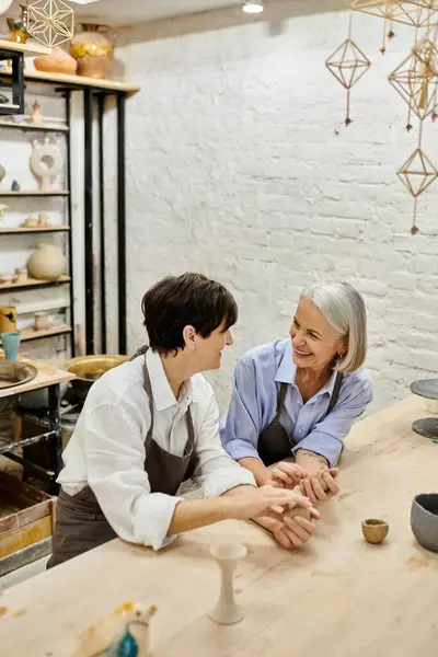 Two women working with clay in a pottery studio, with a relaxed and loving atmosphere. — Stock Photo
