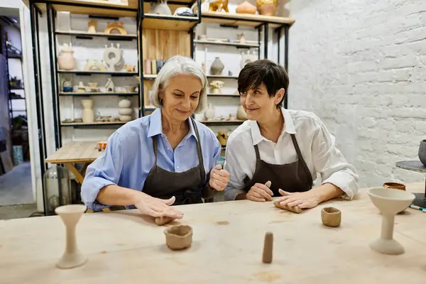 Two mature women craft pottery in a cozy art studio. — Stock Photo