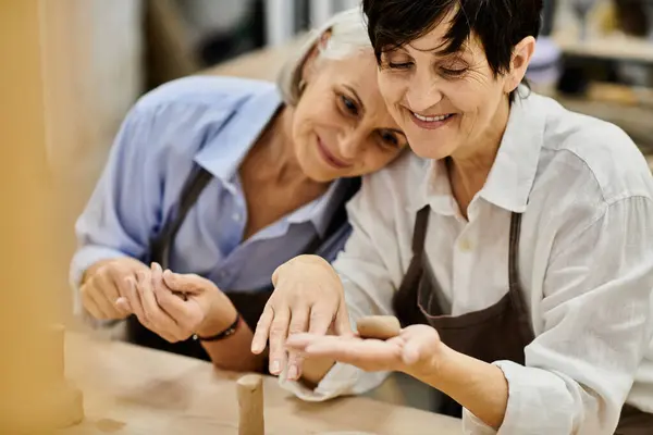 A lesbian couple works on a pottery project together in a studio. — Stock Photo