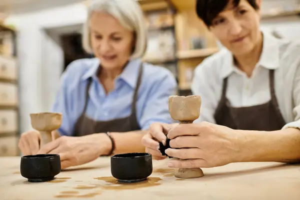 Two mature women create pottery together in a cozy art studio. — Stock Photo