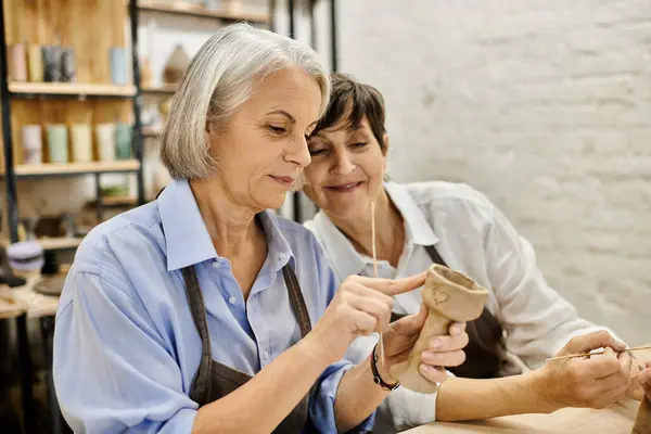 A mature lesbian couple works together on a pottery project in a cozy studio setting. — Stock Photo