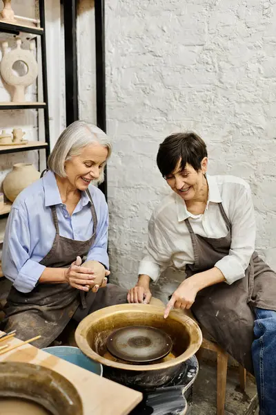 Two women in cozy attire create pottery together in a studio. — Stock Photo