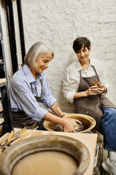 Two women craft together in a pottery studio, enjoying a shared creative moment. — Stock Photo
