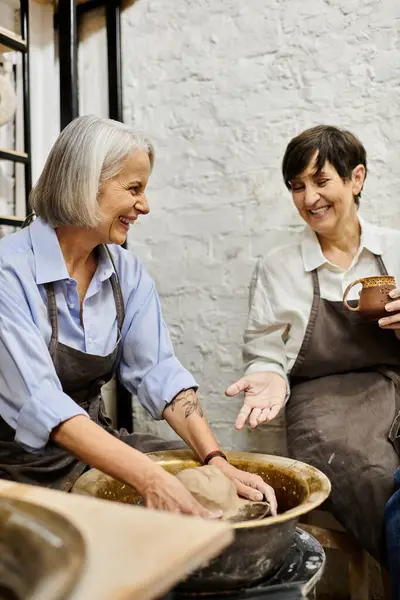 Two women work on pottery in a studio, sharing a laugh and a moment of connection. — Stock Photo