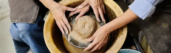 Two women work together on a pottery wheel in a studio setting. — Stock Photo